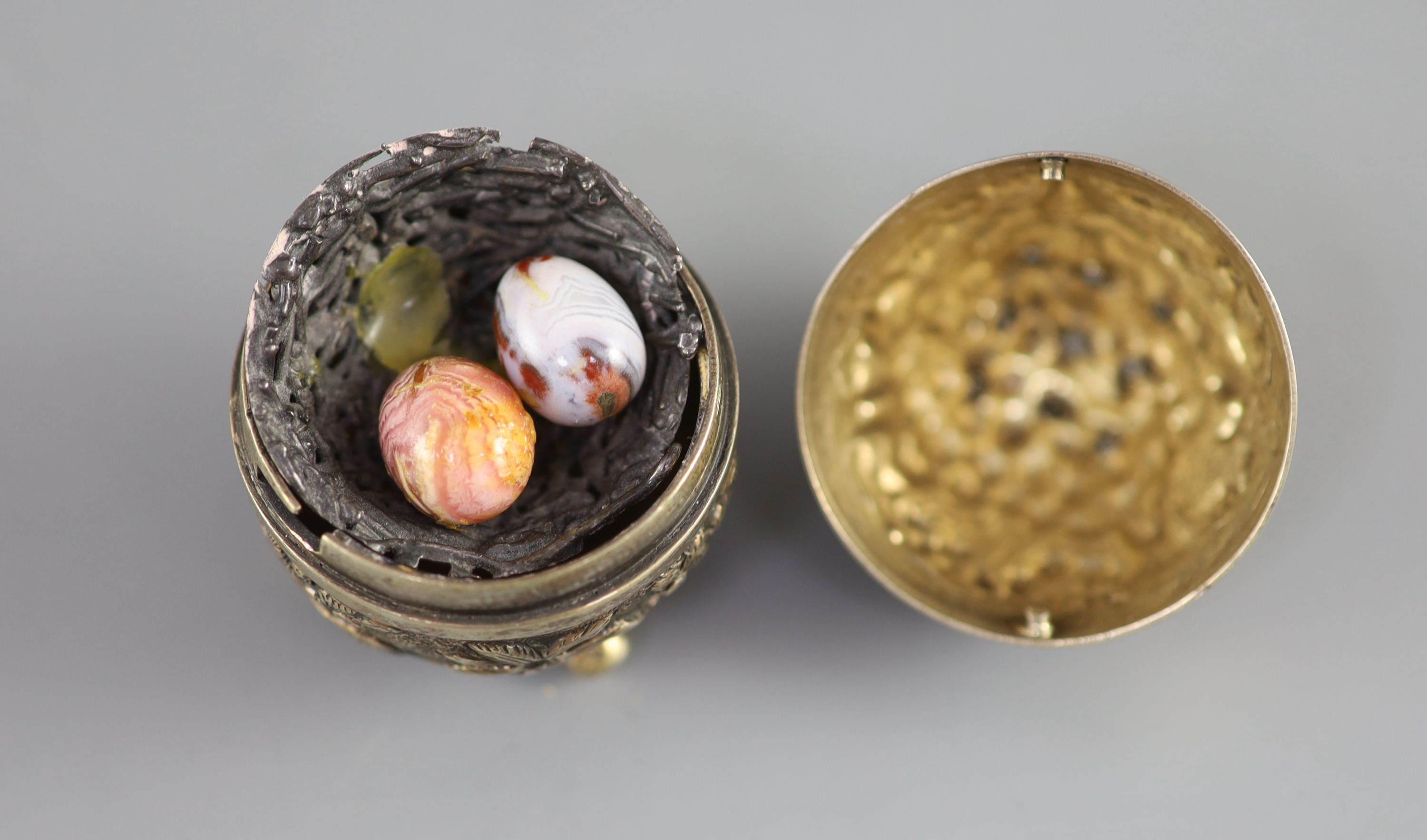 A graduated pair of Edwardian novelty silver gilt condiments, modelled as eggs, with bird's nest interior including two 'marbled' eggs